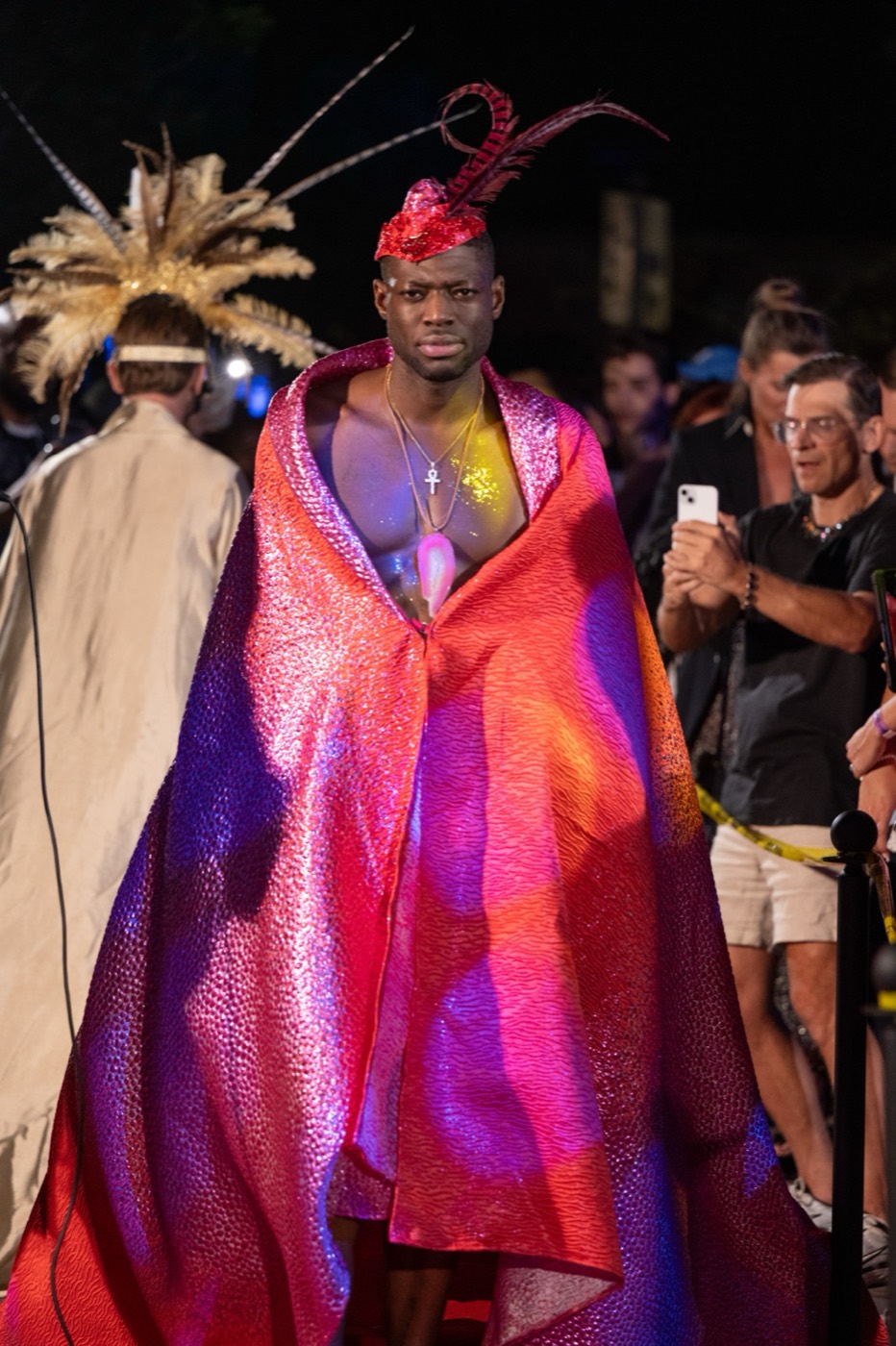 Model in an iridescent garment and feathered headdress at a night fashion show